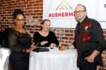 three people stand at table in front of ausherman family foundation sponsor sign